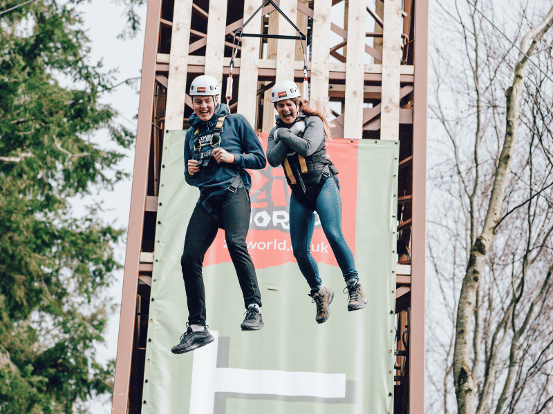 Two people smiling on a freefall adventure with trees in the background